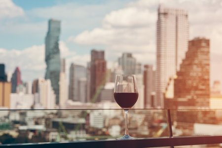 red wine on terrace with Bangkok city skyline at sunset, cocktail on rooftop, vibrant cityscape and luxury panorama viewの写真素材