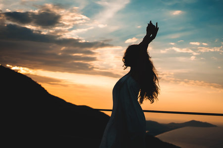 Silhouette woman raising arms at mountain sunset view, Backlit female posing with raised hands...