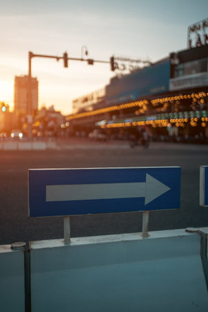 Directional arrow road sign at urban intersection during warm sunset at city atmosphere, Traffic...