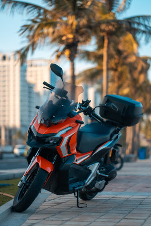 Modern sporty motorcycle parked on tropical city street with palm trees at sunset, Stylish urban...