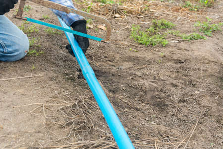 Plumber sawing a pvc pipe at fieldの写真素材