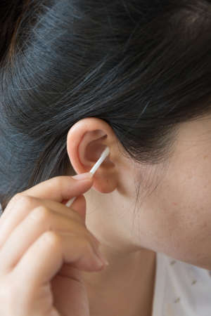 Woman cleaning the ears with a cotton stalkの写真素材