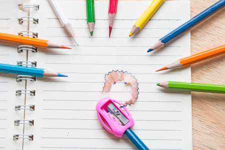 Pencil colored with sharpener and sharpening shaving on notebook