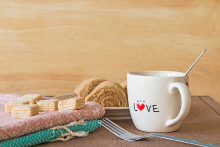 Coffee with wafers and cake roll on wooden backgroundの写真素材