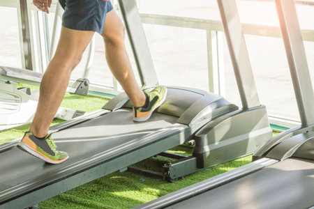 Close-up of man walking by treadmill in sports club,moving scene