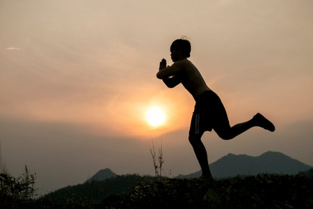 Fit man practices yoga with sunset background
