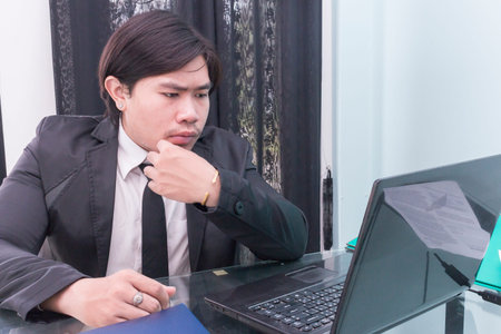 Young businessman using laptop at desk in office,Asian businessman