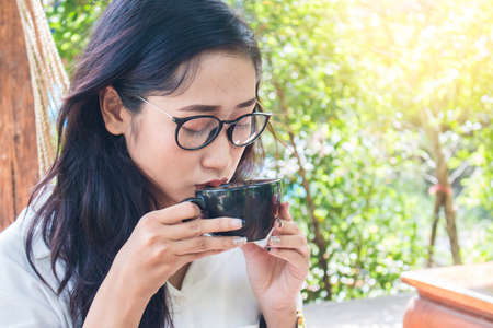 beautiful asian women drink coffee in gardenの写真素材