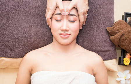 High angle view of an attractive young asian woman receiving facial massage at spa centerの写真素材