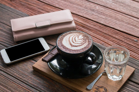 Hot chocolate with smart phone,wallet on wooden table