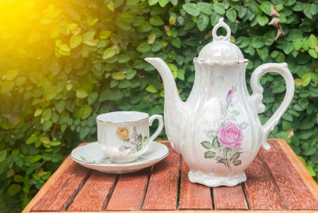 ceramic tea pot and cup on wood table in green leaf backgroundの写真素材