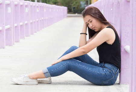 Young women sitting on the floor on bridge,sad emotionの写真素材