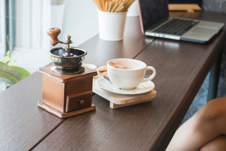 Coffee grinder with coffee cup on table in cafeの写真素材