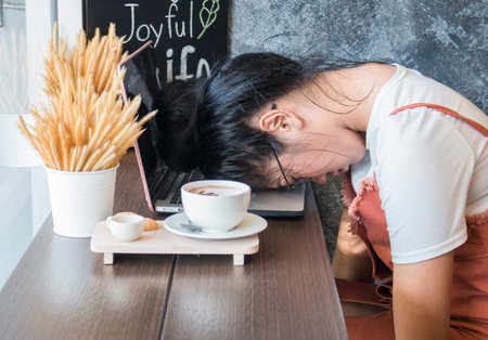 Tired hipster businesswoman sleeping on table in cafe