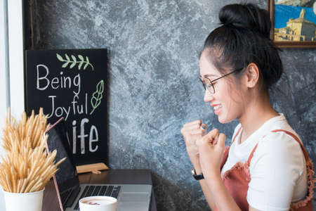 Young asian women winning watching a laptop on a desk winning at cafeの写真素材