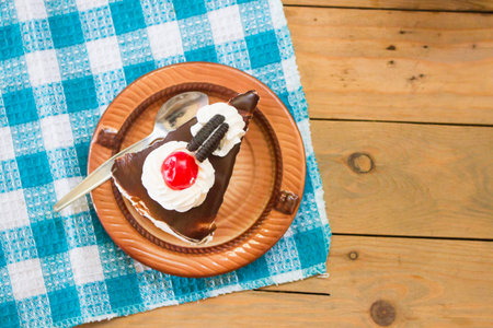 a slice of black chocolate cake with red cherry on napkinの写真素材