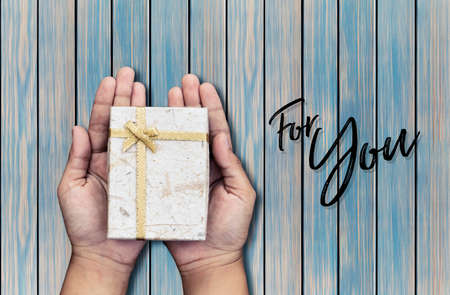 Female hands holding gift on wooden background,for youの写真素材