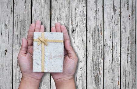 Female hands holding gift on wooden background,copy spaceの写真素材