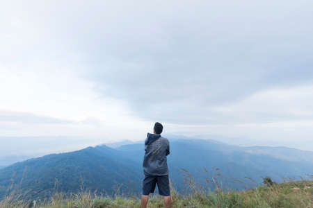 Young man standing on top of mountainの写真素材