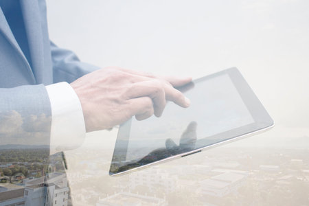 Business hand holding tablet double exposure city background