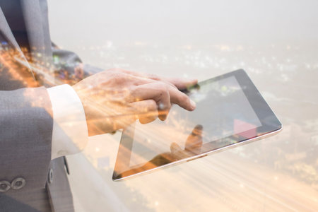 Business hand holding tablet double exposure city backgroundの写真素材