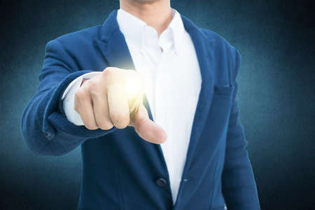 Businessman in suit points on something  on dark backgroundの写真素材
