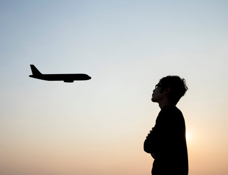 Silhouette of young men alone  seeing plane at passenger on sunset sky