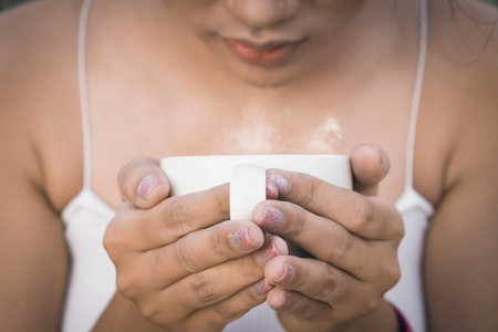 Woman's hand holding a white cup of coffee with smoke