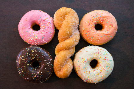 spiral donut with four glazed donut lying on wooden background