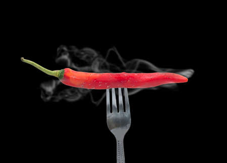 Red chili pepper is pierced a fork with smoke,food conceptの写真素材