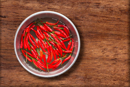 Top view of red chilli pepper in water on bowl of steel on wooden background,copy spaceの写真素材