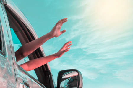 Children  hands out of the car window driving with skyの写真素材