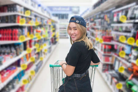 Young asian woman pushing shopping cart in shopping mallの写真素材