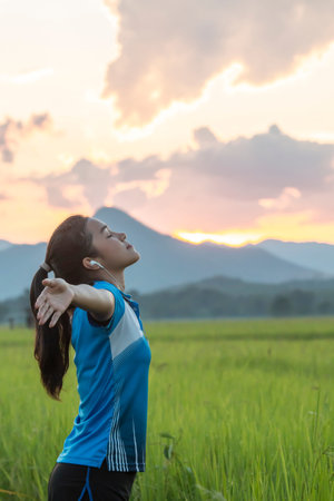 Young asian woman enjoying spring breeze in rice field with sunset