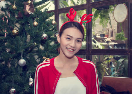 asian woman is wearing chrismas reindeer with chriamas treeの写真素材