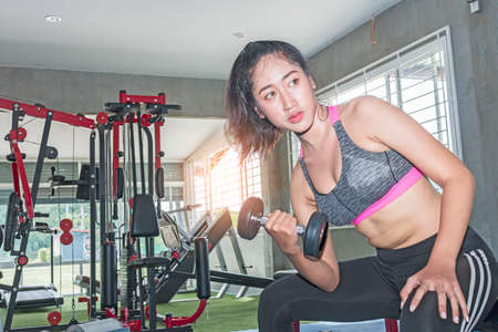 Asian  woman lifting weights in gym as part of her trainingの写真素材