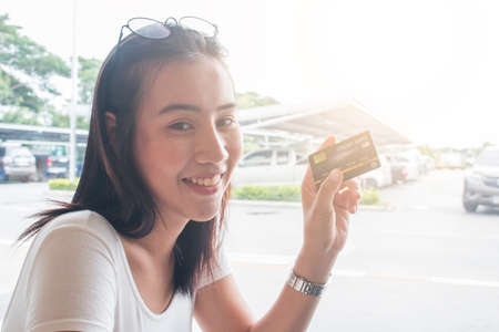 Smiling asian young female model holding up credit card.の写真素材