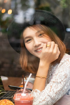A shot of a beautiful asian woman  in a cafe (shot through window)の写真素材