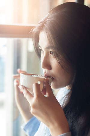 Asian woman drinking hot coffeeの写真素材