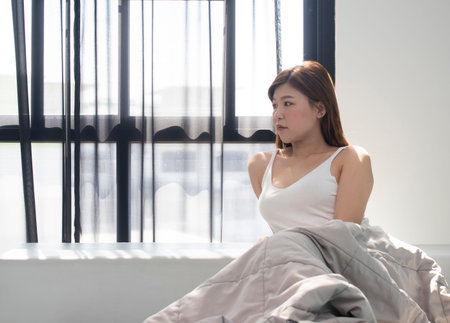 young woman sitting in bed and looks away