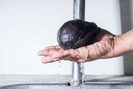Fresh avocado on male hand cleaning with falling waterの写真素材