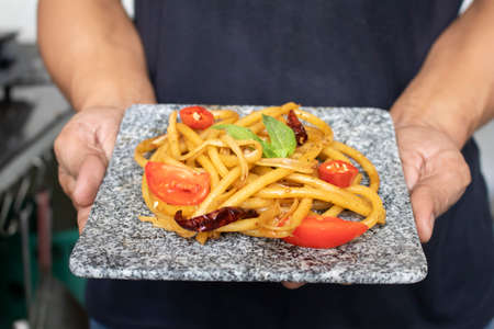 Chef holding hot spaghetti on stone panの写真素材