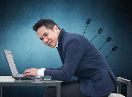 Portrait of young man sitting working on laptop  at his desk on white background,Persistence Concept. 
A man is working harder to achieve new sales target.の写真素材