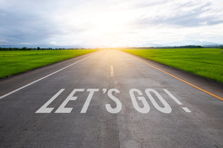 The word let's go written on highway road in the middle of empty asphalt road