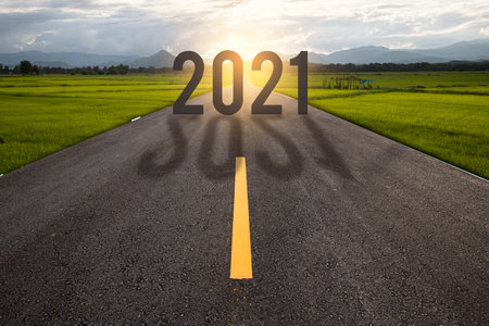 The word 2021 written on highway road in the middle of empty asphalt road at golden sunsetの写真素材