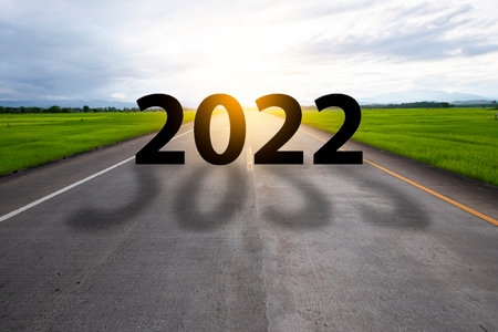 New year 2022 or straightforward concept. Text 2022 written on the road in the middle of asphalt road at sunset.の写真素材