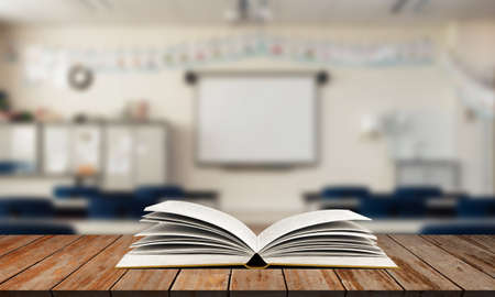 Open book on wooden table with blurred class room backgroundの写真素材