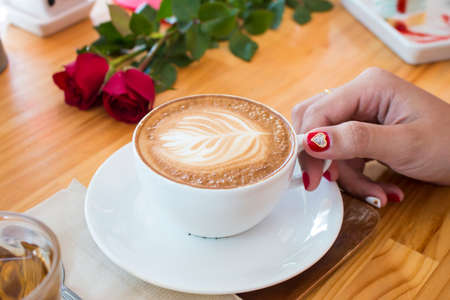 women hand with latte coffee on wood tableの写真素材