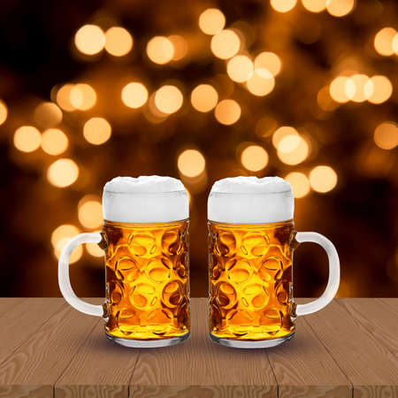 Two glasses of light beer on wooden table with blurred bokeh backgroundの写真素材