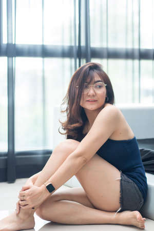 Cute asian girl with eye glass sitting in bed roomの写真素材